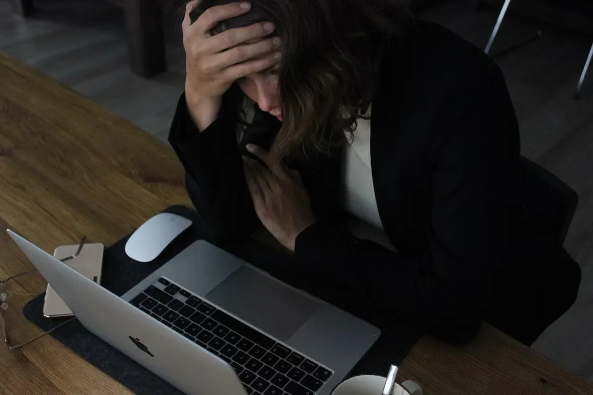Professional woman overwhelmed at laptop, illustrating the challenge of setting boundaries at work when everything feels urgent