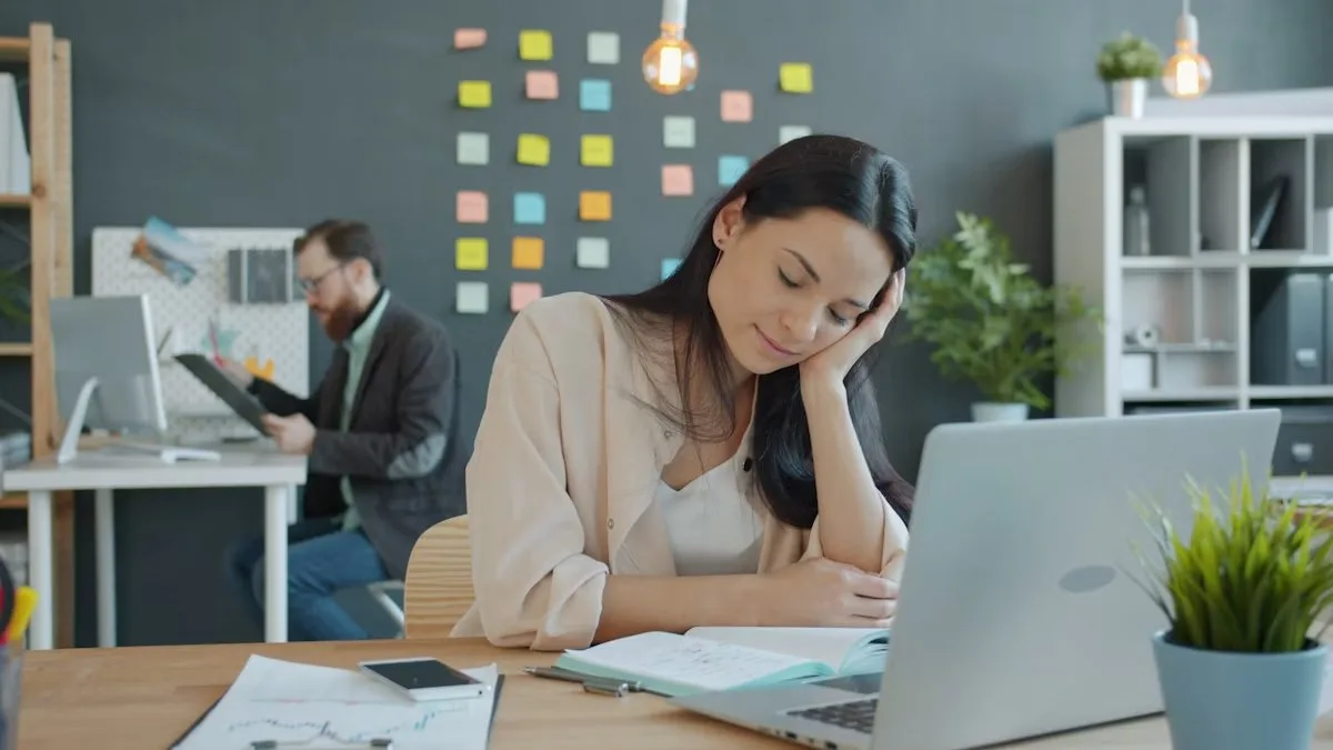Tired woman resting her head on her hand at work, demonstrating the need to learn how to set work boundaries without guilt