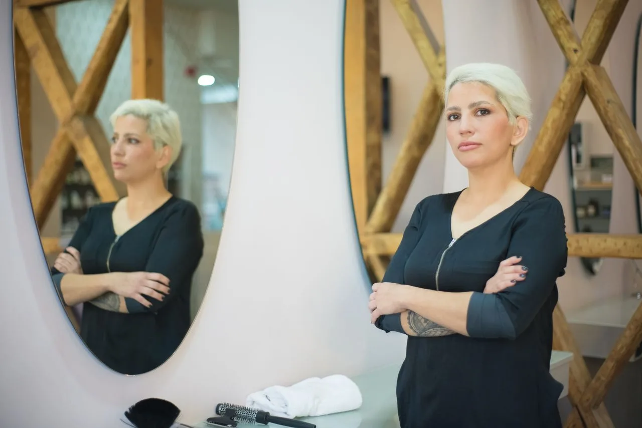 Woman confidently looking at her reflection in a mirror, overcoming self-doubt