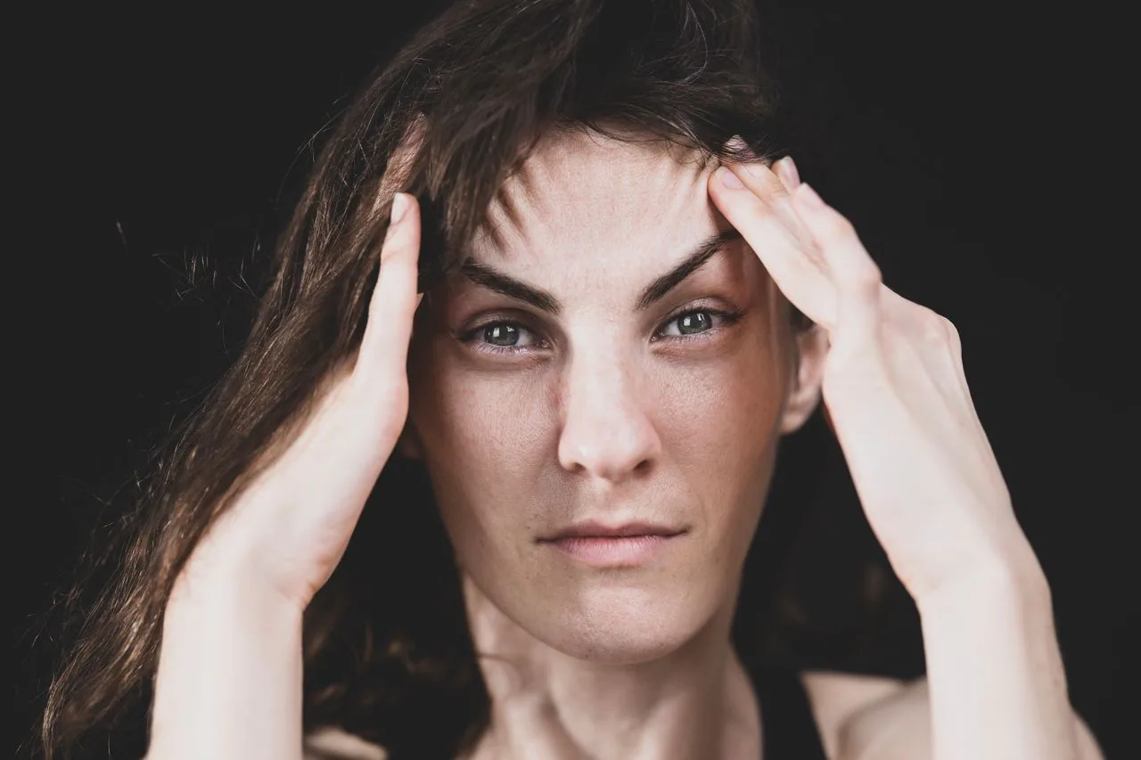 Woman with hands on her temples experiencing stress and second-guessing herself