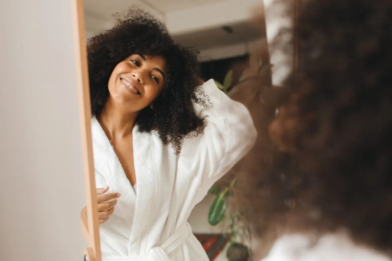 Woman smiling confidently at her reflection in the mirror, overcoming self-doubt and second-guessing