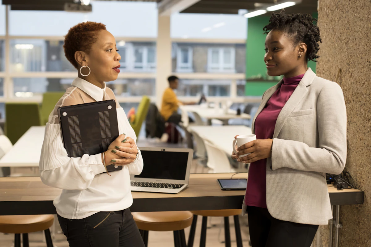 Two women at work talking through workload priorities during burnout recovery