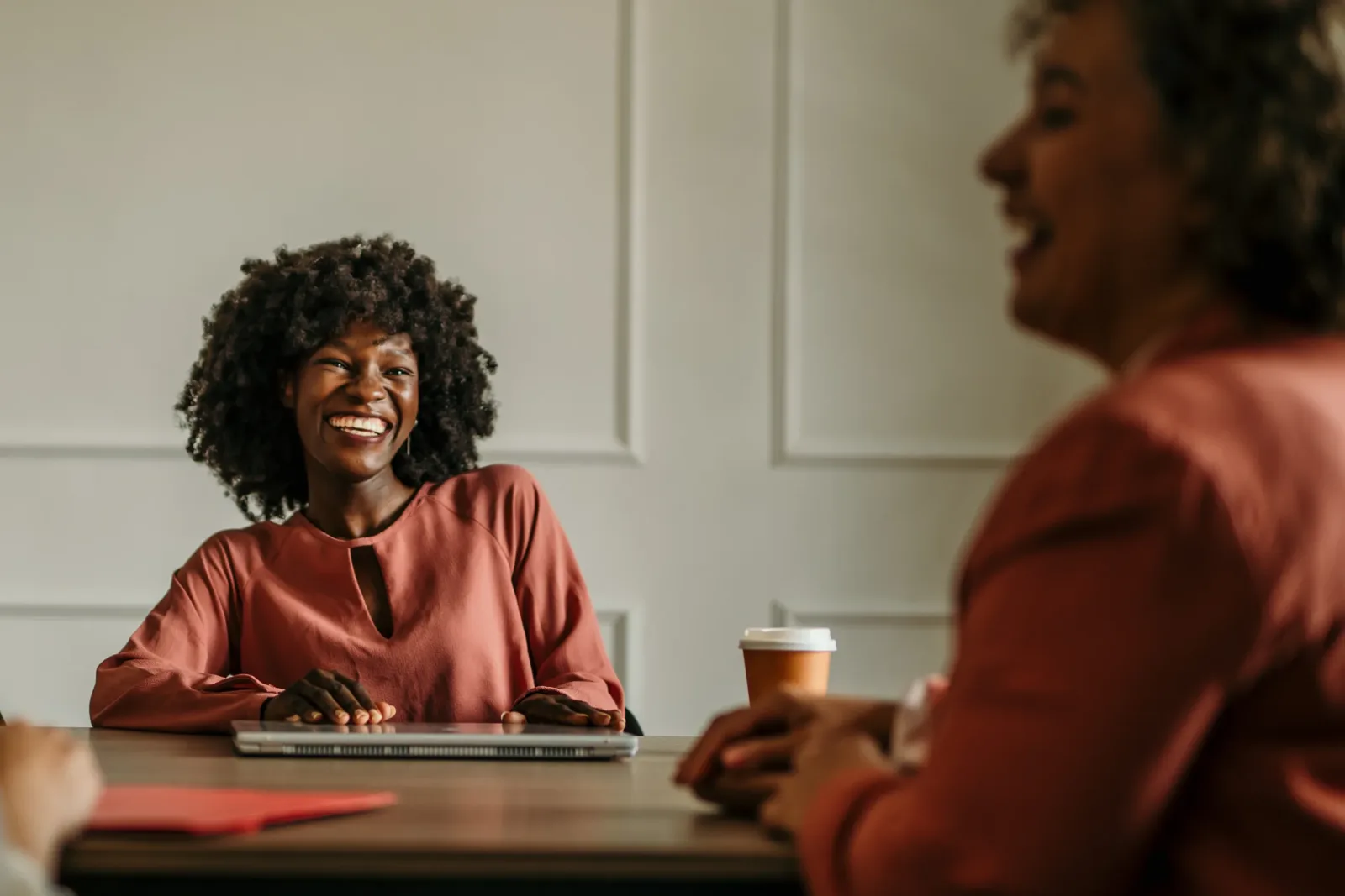 Smiling woman in a one-on-one conversation, weighing a life coach vs therapist