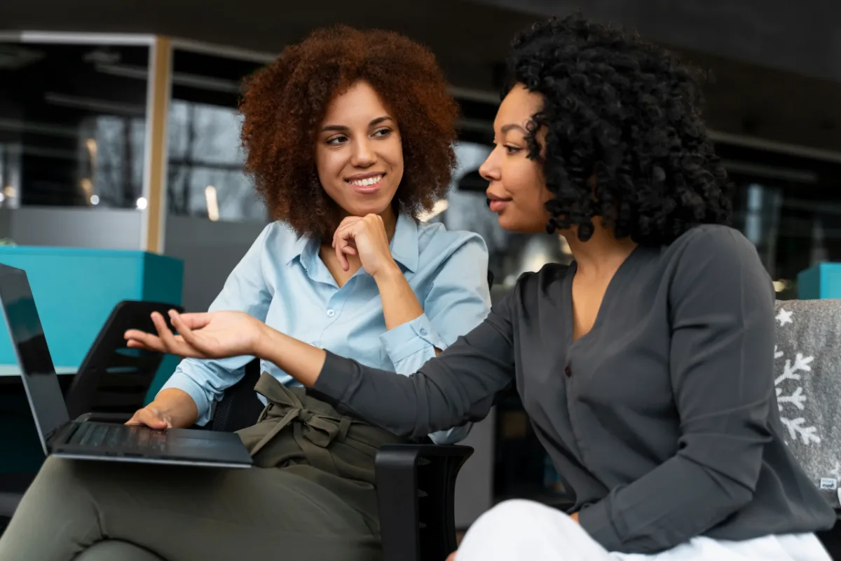Two women in a personal development coaching session, talking through goals at a laptop