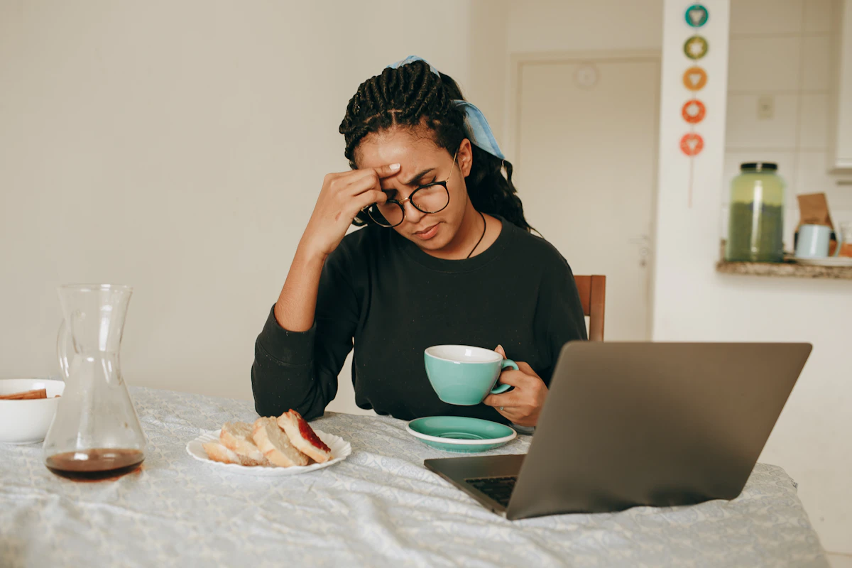 Woman recovering from burnout while still working at her laptop with a cup of coffee